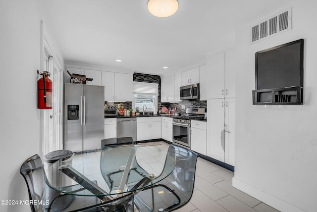 kitchen with decorative backsplash, stainless steel appliances, white cabinetry, and sink