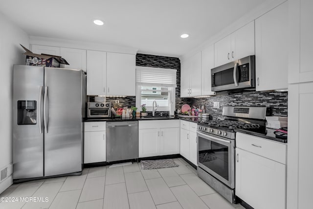 kitchen featuring stainless steel appliances, white cabinetry, tasteful backsplash, and sink