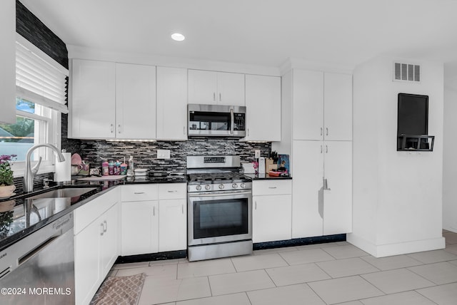 kitchen with appliances with stainless steel finishes, white cabinetry, sink, and tasteful backsplash