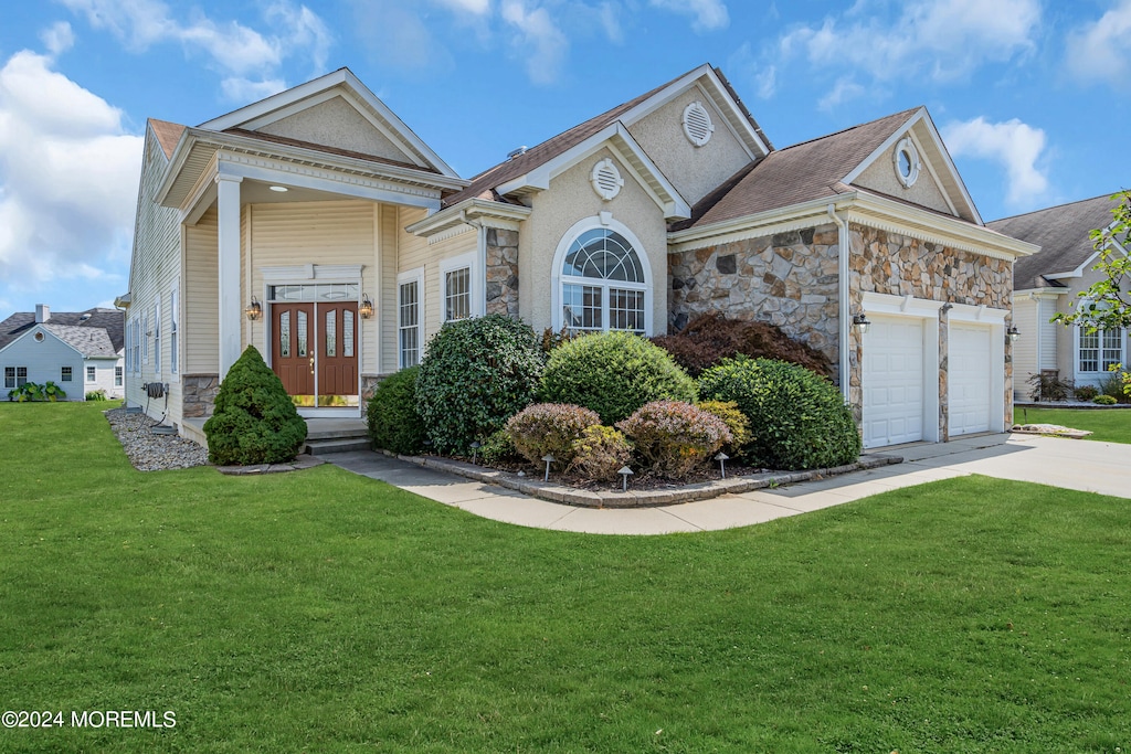 view of front facade with a front lawn, a garage, and french doors