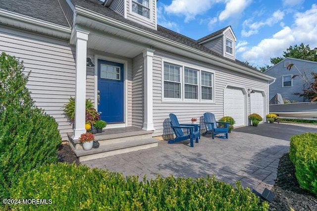 view of exterior entry featuring a garage and aphalt driveway