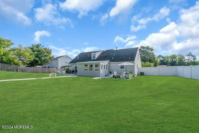 back of property with a fenced backyard and a lawn