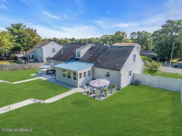 rear view of house with a yard, a fenced backyard, cooling unit, and a patio