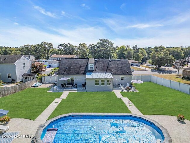 rear view of property with a yard, a patio, a fenced backyard, and a fenced in pool