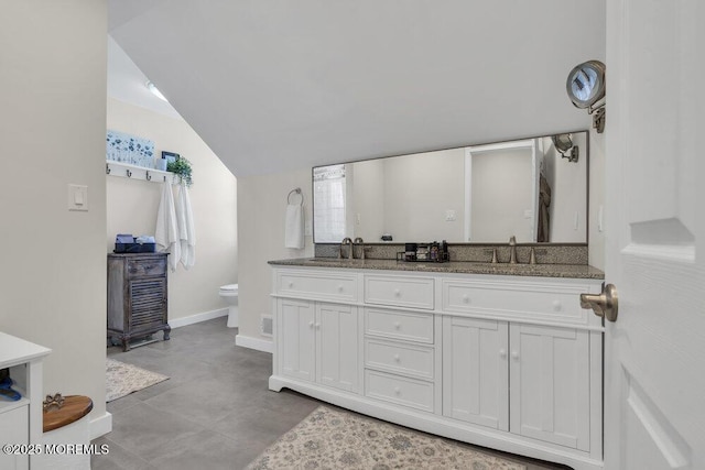 full bath with lofted ceiling, a sink, toilet, and double vanity