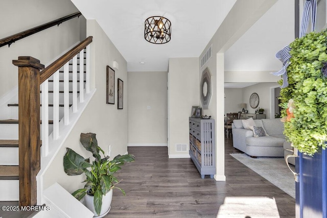 entrance foyer with stairs, visible vents, and wood finished floors