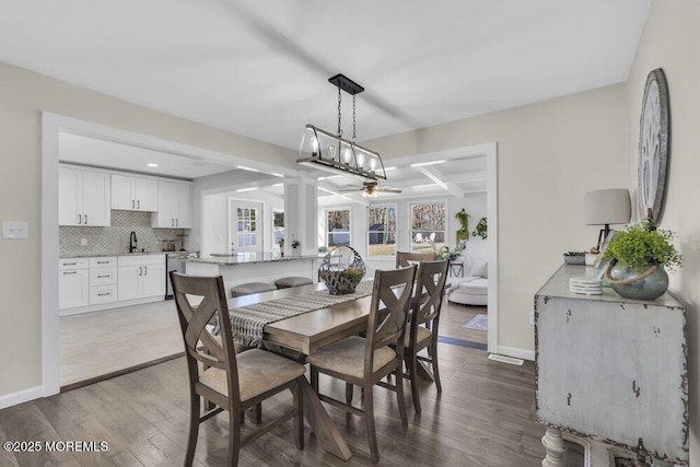 dining area featuring baseboards, coffered ceiling, wood finished floors, and beamed ceiling