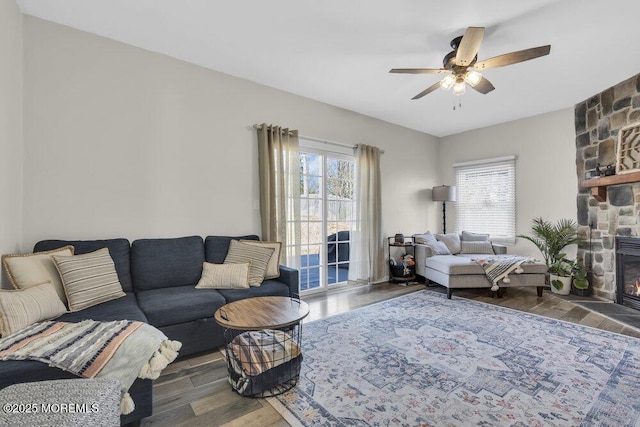 living room featuring a fireplace, wood finished floors, and a ceiling fan