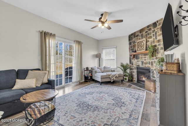 living room with ceiling fan, a fireplace, and wood finished floors