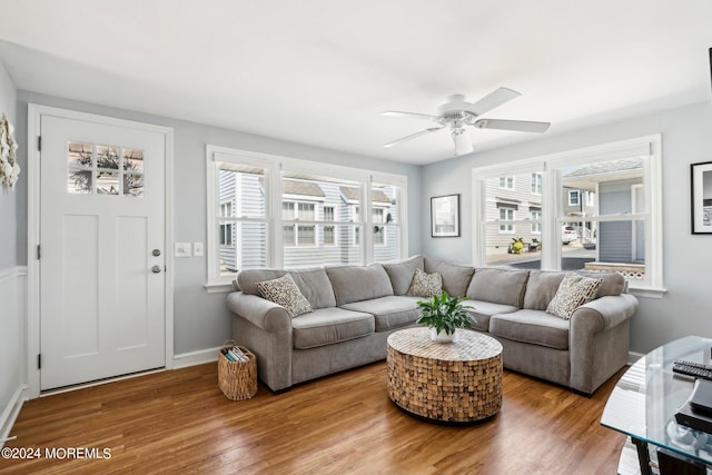 living area with wood finished floors, a ceiling fan, and baseboards