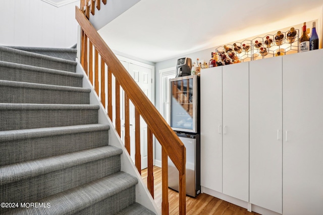 staircase featuring wood finished floors and wine cooler