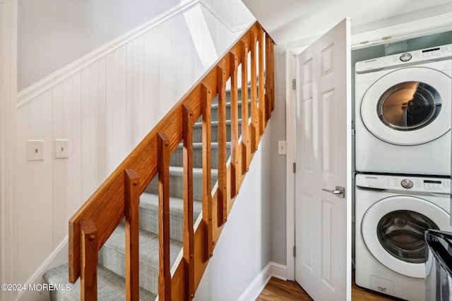 laundry room featuring stacked washing machine and dryer, baseboards, and wood finished floors