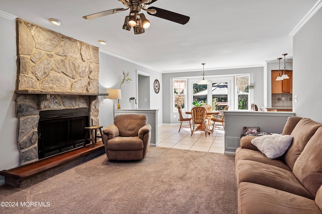 living room featuring ceiling fan, light colored carpet, crown molding, and a stone fireplace