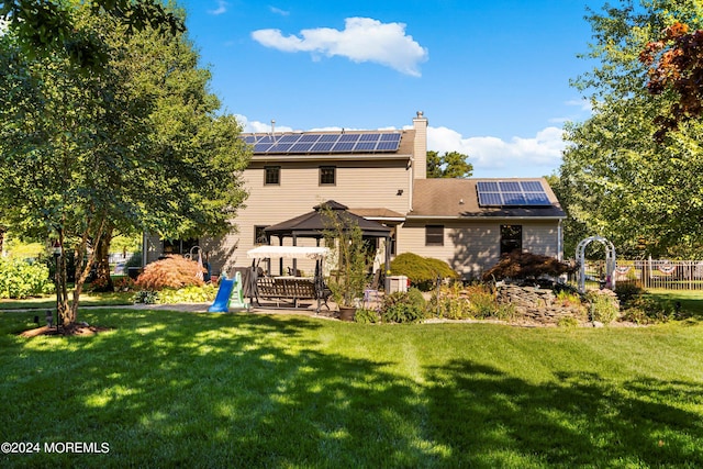 back of property with a lawn, a gazebo, and solar panels