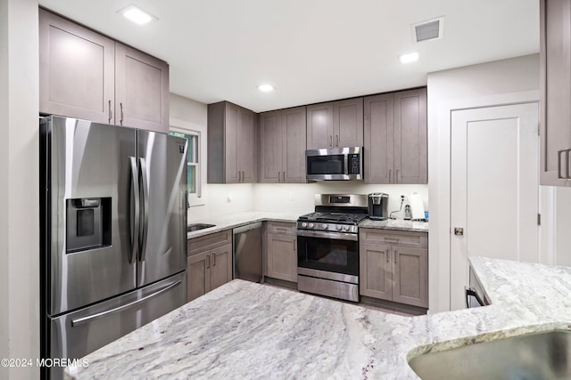 kitchen featuring appliances with stainless steel finishes and light stone counters