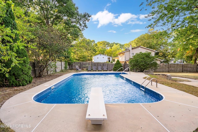 view of pool with a diving board and a patio