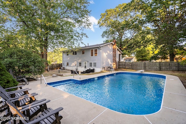 view of swimming pool with a diving board and a patio area