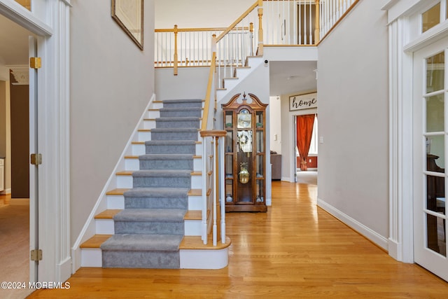 staircase featuring wood-type flooring and a towering ceiling