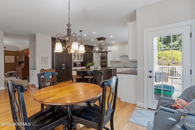 dining area featuring light hardwood / wood-style floors, an inviting chandelier, and crown molding