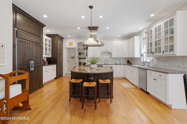 kitchen featuring light stone countertops, white cabinets, built in appliances, light hardwood / wood-style floors, and a kitchen island