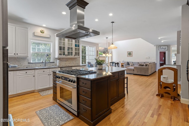 kitchen featuring white cabinetry, sink, island range hood, stainless steel stove, and light wood-type flooring