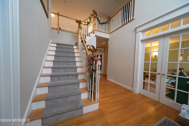 stairs featuring french doors, a high ceiling, and hardwood / wood-style floors