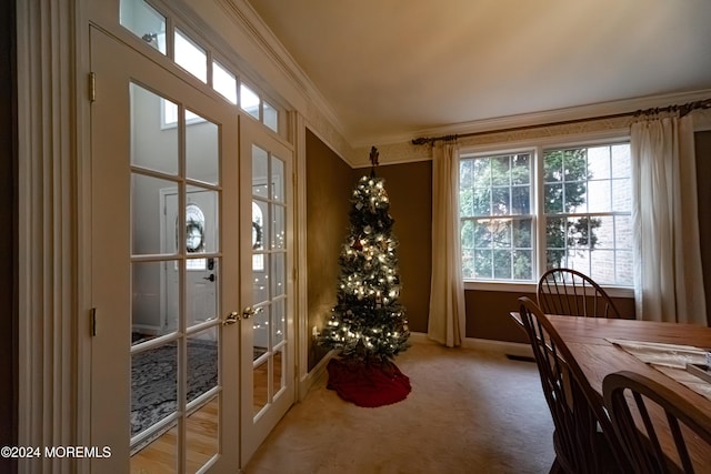 carpeted dining room featuring crown molding and french doors