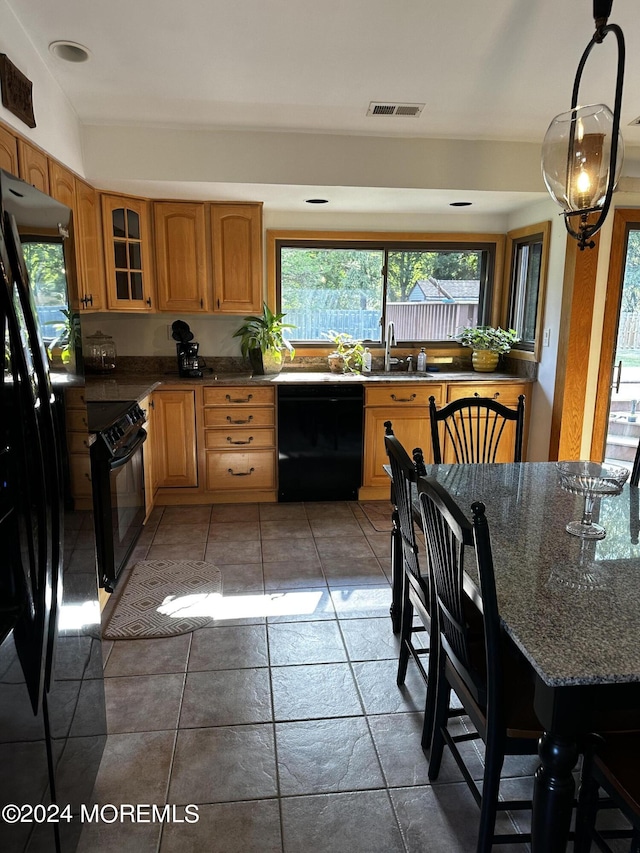 kitchen featuring black appliances, dark stone countertops, sink, and decorative light fixtures