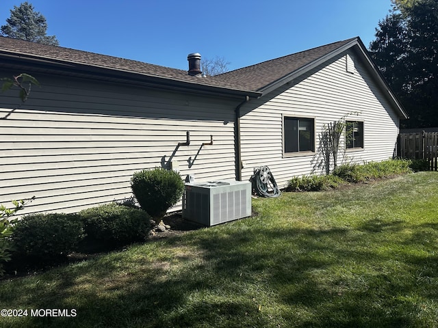 view of property exterior with a yard and central air condition unit