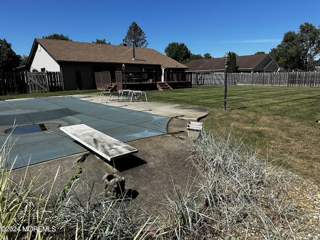 view of swimming pool with a diving board, a lawn, and a patio area