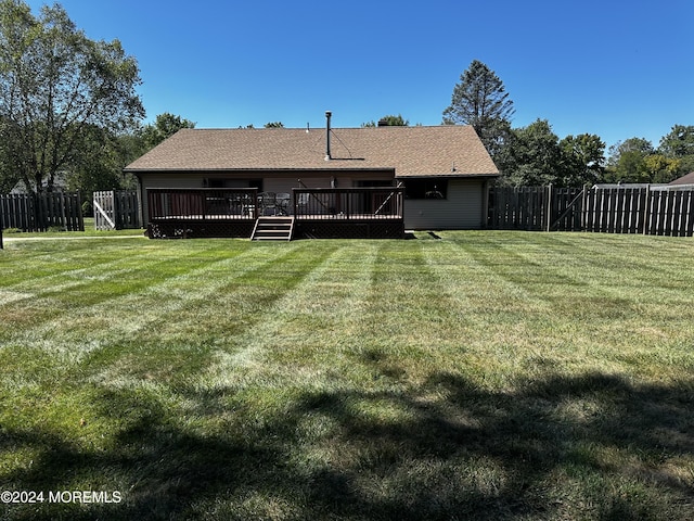 rear view of property featuring a deck and a lawn