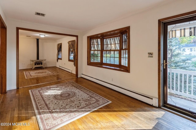 interior space featuring a wood stove, wood-type flooring, and a baseboard radiator