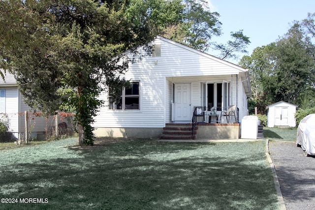 view of front of home with a storage unit and a front yard