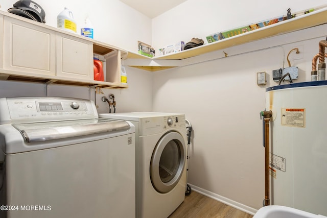 washroom with light hardwood / wood-style flooring, water heater, cabinets, and separate washer and dryer