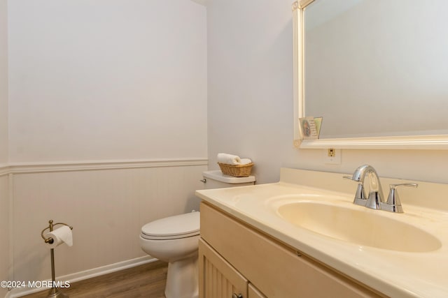 bathroom with hardwood / wood-style floors, vanity, and toilet