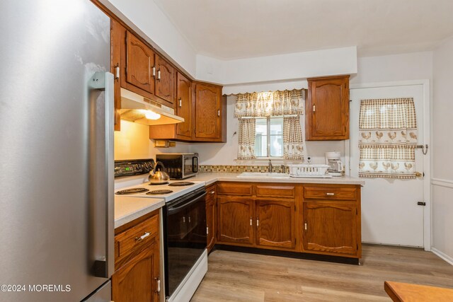 kitchen featuring stainless steel appliances, light wood-type flooring, and sink