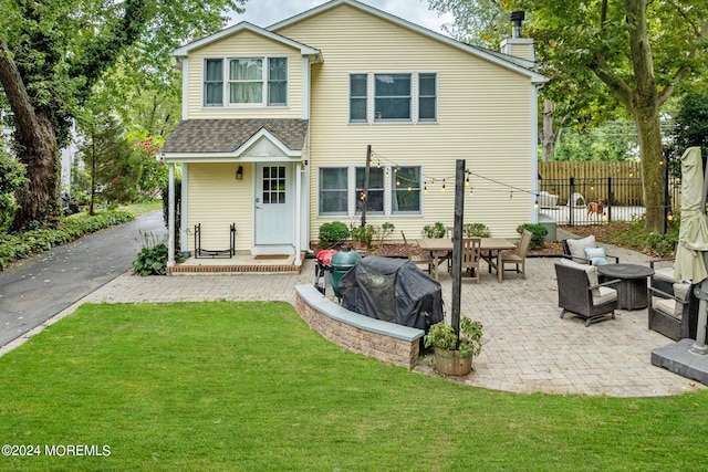 rear view of property featuring outdoor lounge area, a patio area, and a yard