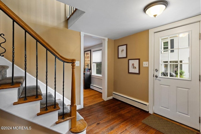 foyer entrance with dark wood-type flooring, a baseboard heating unit, and plenty of natural light