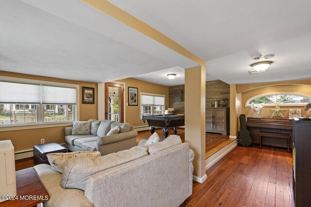 living room with vaulted ceiling, baseboard heating, a healthy amount of sunlight, and dark hardwood / wood-style flooring