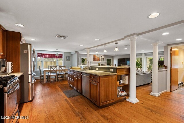 kitchen featuring appliances with stainless steel finishes, hanging light fixtures, decorative columns, and sink