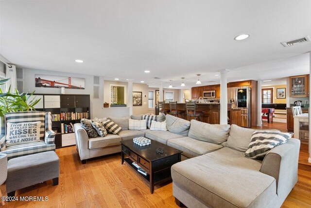 living room with light wood-type flooring and ornate columns