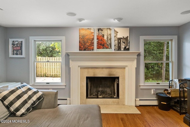 living room with light hardwood / wood-style floors, baseboard heating, and a high end fireplace