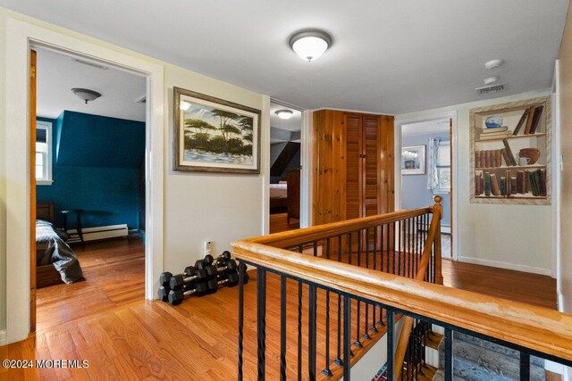 hall featuring a baseboard heating unit and wood-type flooring