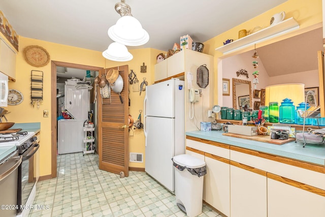 kitchen with pendant lighting, stove, white fridge, and white cabinetry