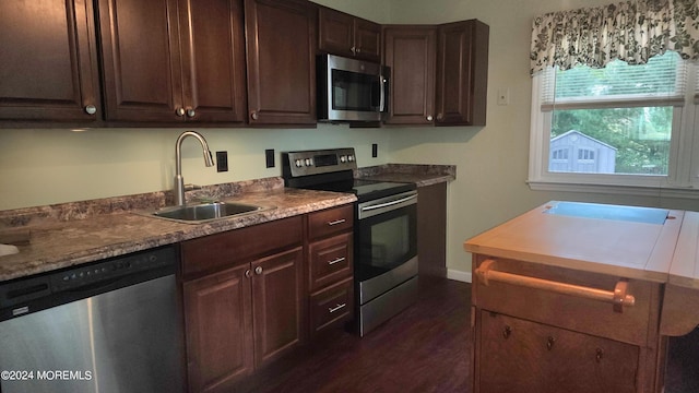 kitchen with dark brown cabinetry, appliances with stainless steel finishes, dark wood-type flooring, and sink