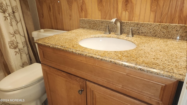 bathroom with wooden walls, vanity, and toilet