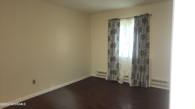 empty room with baseboard heating and dark wood-type flooring