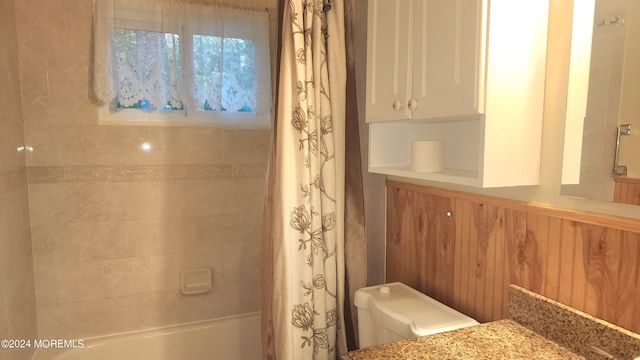 bathroom with shower / bath combo, wood walls, and toilet