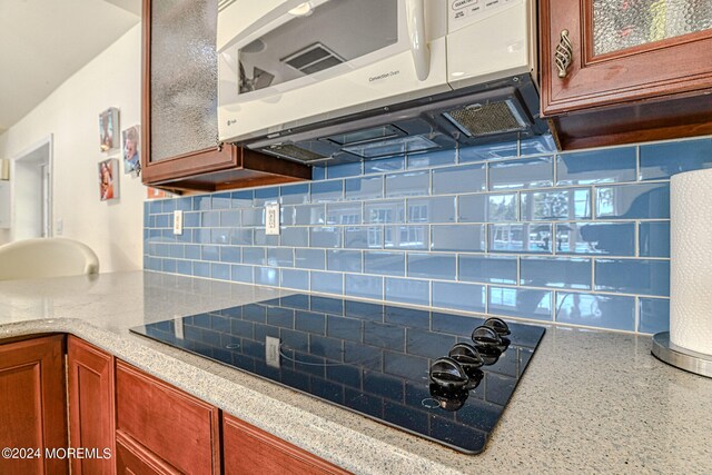 kitchen with decorative backsplash and black stovetop