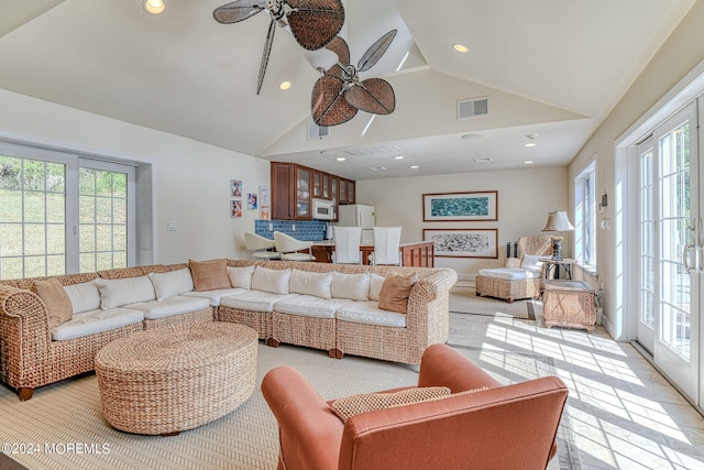 tiled living room with ceiling fan and high vaulted ceiling